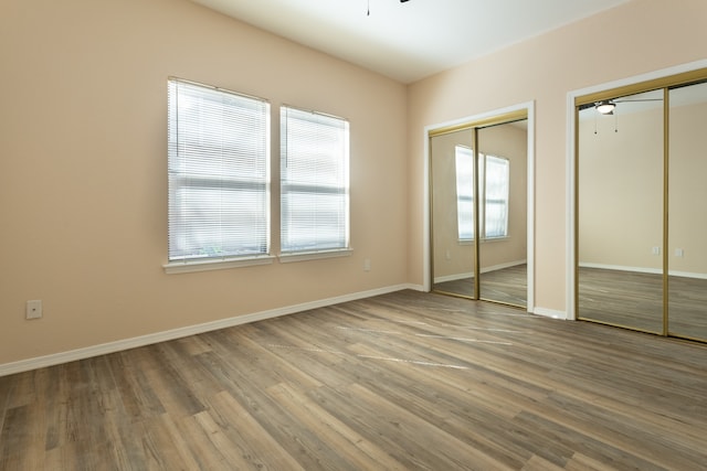 unfurnished bedroom with multiple closets, hardwood / wood-style floors, and multiple windows