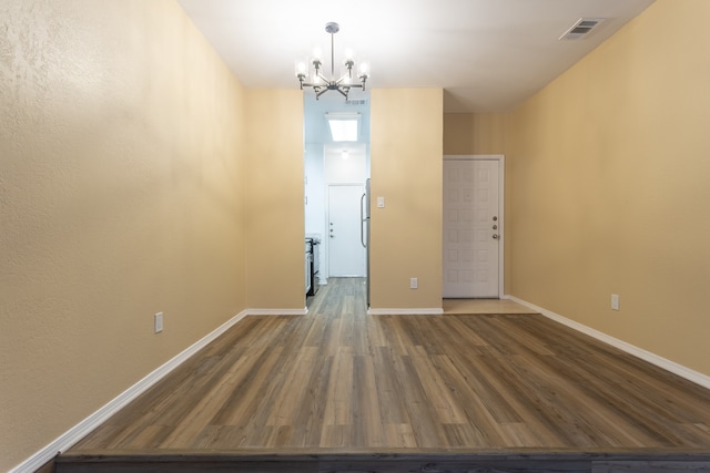 unfurnished room with a chandelier and wood-type flooring