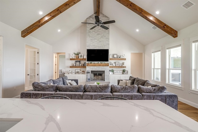 living room featuring a fireplace, beamed ceiling, hardwood / wood-style floors, and high vaulted ceiling