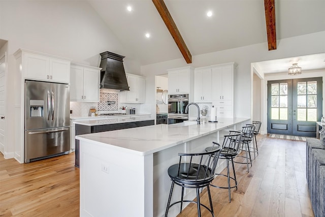 kitchen with beam ceiling, light hardwood / wood-style flooring, stainless steel appliances, and custom range hood