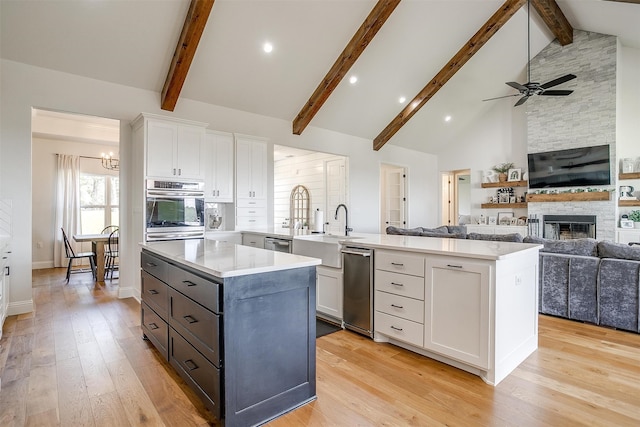 kitchen with a fireplace, white cabinets, appliances with stainless steel finishes, and a center island