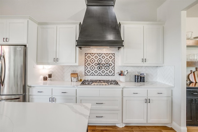 kitchen featuring white cabinetry, stainless steel appliances, and custom exhaust hood