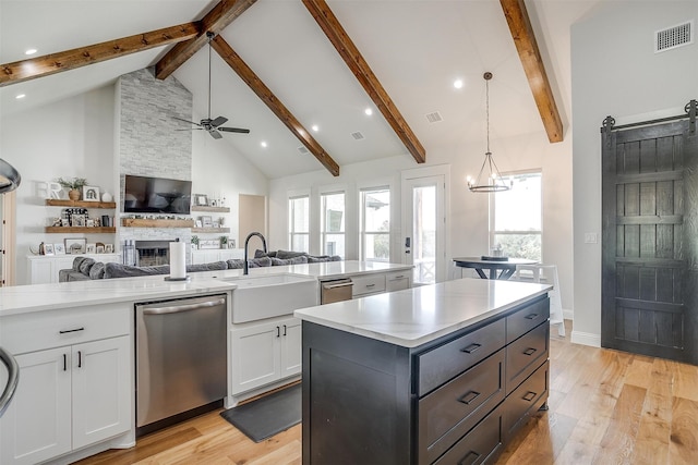 kitchen featuring a center island, stainless steel dishwasher, white cabinets, a barn door, and light hardwood / wood-style flooring