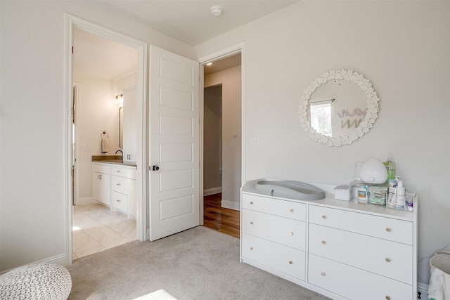 carpeted bedroom featuring connected bathroom and sink