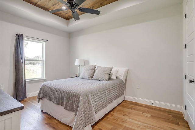 bedroom with ceiling fan, a raised ceiling, light hardwood / wood-style floors, and wooden ceiling