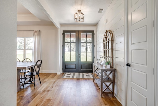 doorway featuring light wood-type flooring, a healthy amount of sunlight, french doors, and an inviting chandelier