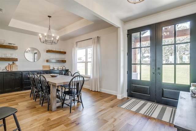 dining room with french doors, ornamental molding, a raised ceiling, and light hardwood / wood-style floors