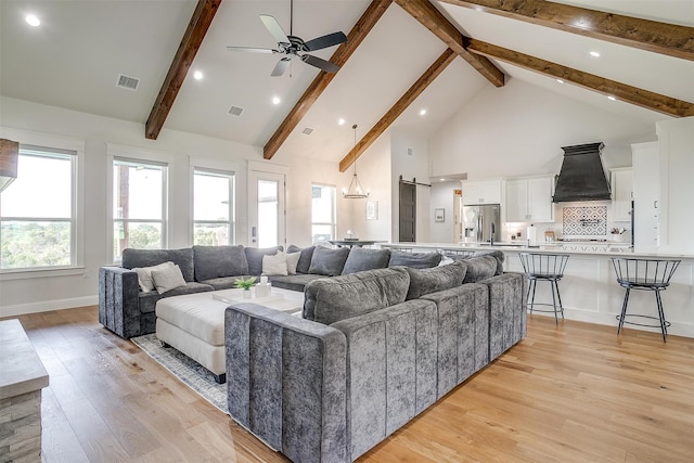 living room with light wood-type flooring, high vaulted ceiling, ceiling fan, beamed ceiling, and a barn door