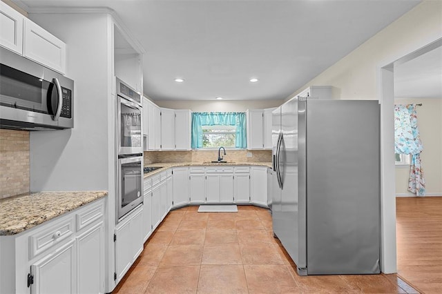 kitchen with backsplash, white cabinets, light hardwood / wood-style floors, and appliances with stainless steel finishes