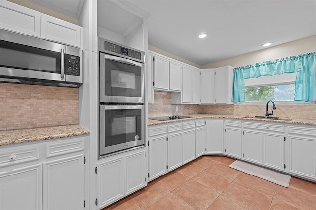 kitchen with tasteful backsplash, stainless steel appliances, sink, white cabinets, and light tile patterned flooring