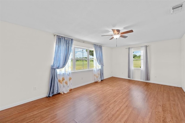 unfurnished room with a wealth of natural light, ceiling fan, and light wood-type flooring