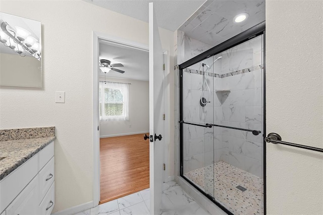 bathroom featuring ceiling fan, vanity, wood-type flooring, and walk in shower