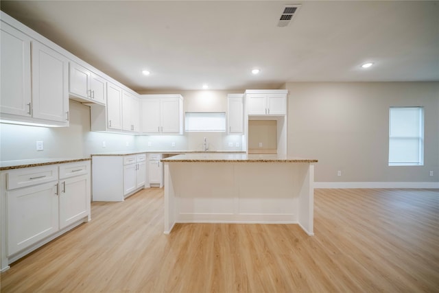 kitchen featuring white cabinetry, light wood-type flooring, sink, and a kitchen island