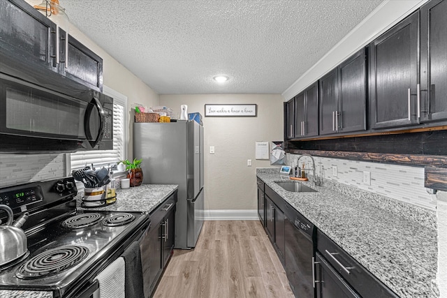 kitchen featuring black appliances, light stone counters, sink, and light hardwood / wood-style flooring