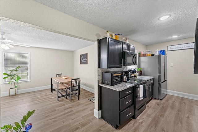 kitchen featuring a textured ceiling, stainless steel appliances, light hardwood / wood-style flooring, and ceiling fan