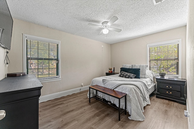 bedroom with hardwood / wood-style floors, ceiling fan, and a textured ceiling