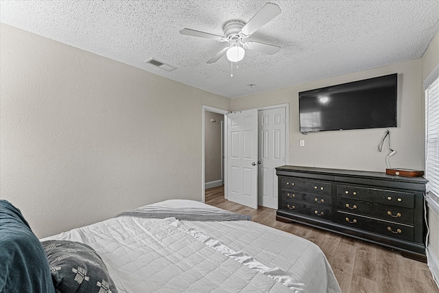 bedroom featuring ceiling fan, dark hardwood / wood-style flooring, and a textured ceiling