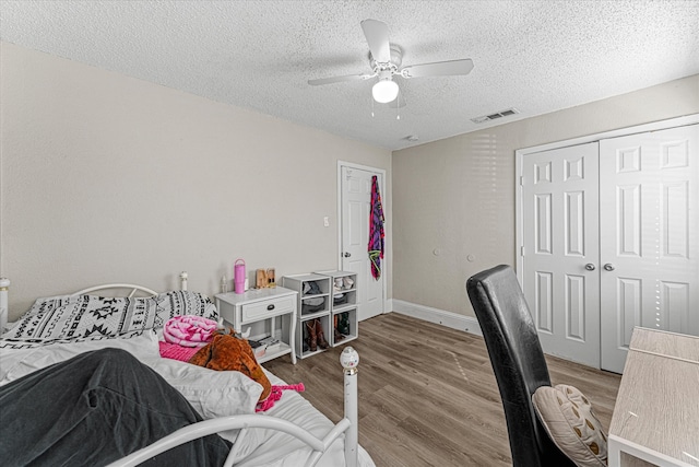 bedroom with ceiling fan, a closet, hardwood / wood-style floors, and a textured ceiling