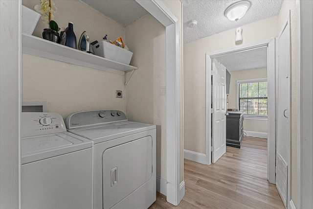 laundry area with washer and clothes dryer, light hardwood / wood-style floors, and a textured ceiling