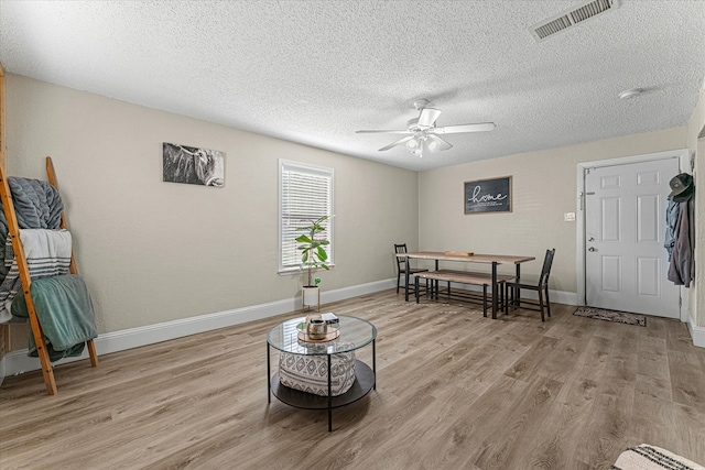 sitting room with a textured ceiling, light wood-type flooring, and ceiling fan