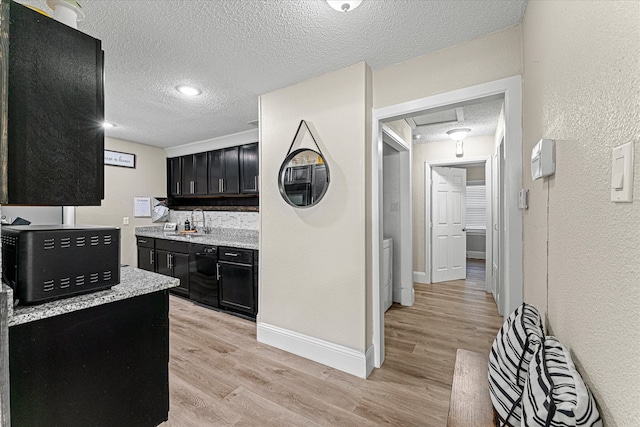 kitchen featuring light stone countertops, light wood-type flooring, a textured ceiling, sink, and dishwasher