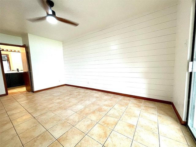 empty room featuring ceiling fan and wooden walls