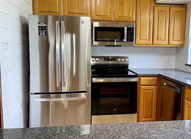 kitchen with dark stone countertops and stainless steel appliances