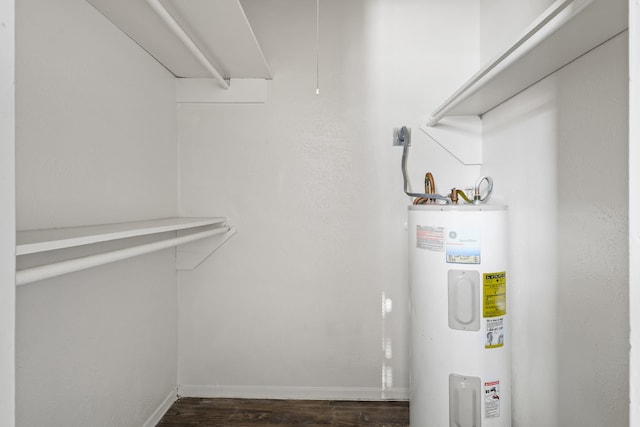 spacious closet with dark wood-type flooring and electric water heater