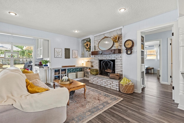 living room with a fireplace, a textured ceiling, and dark wood-type flooring