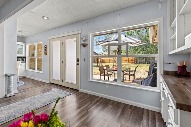 doorway with dark hardwood / wood-style floors, a healthy amount of sunlight, and a textured ceiling