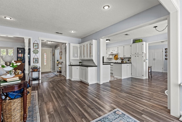 kitchen with dark hardwood / wood-style flooring, white cabinets, and a textured ceiling