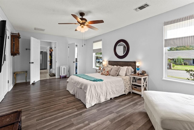 bedroom with multiple windows, a textured ceiling, ceiling fan, and dark wood-type flooring