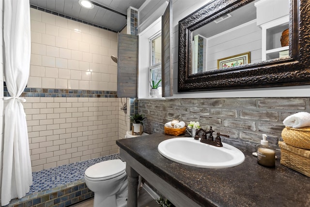 bathroom featuring tiled shower, toilet, decorative backsplash, and sink