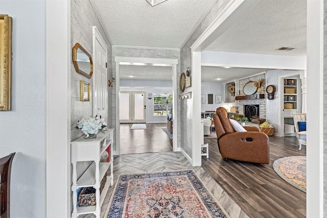 foyer featuring a textured ceiling, a brick fireplace, and parquet floors