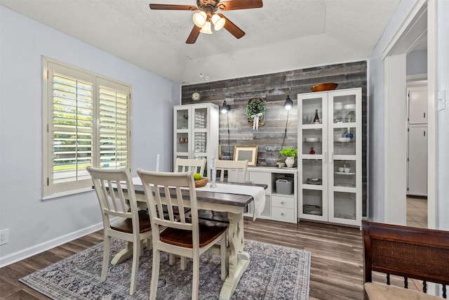 dining space with dark hardwood / wood-style flooring, a textured ceiling, ceiling fan, and wood walls