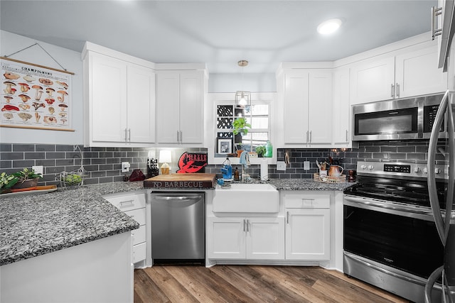 kitchen featuring sink, dark wood-type flooring, pendant lighting, white cabinets, and appliances with stainless steel finishes