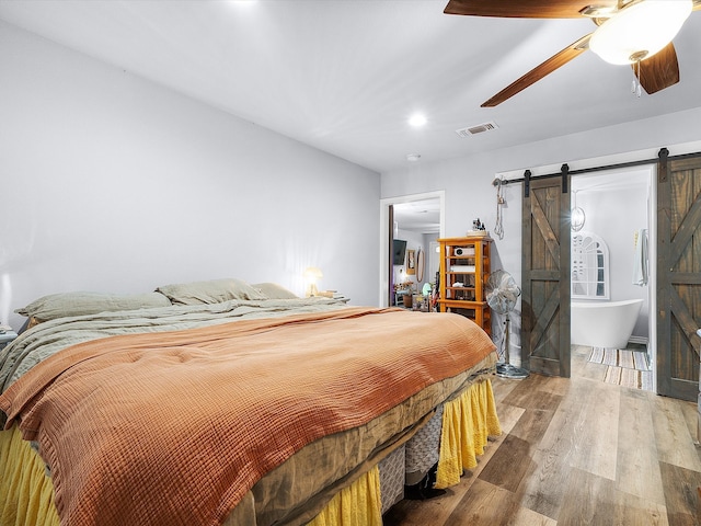 bedroom featuring a barn door, ceiling fan, and hardwood / wood-style floors