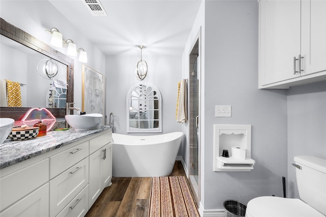 bathroom with hardwood / wood-style floors, vanity, a bath, and toilet