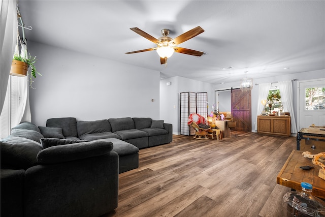 living room featuring ceiling fan, a barn door, and wood-type flooring