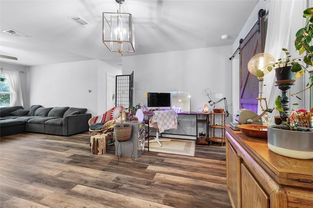 living room featuring a barn door, dark hardwood / wood-style flooring, and a chandelier