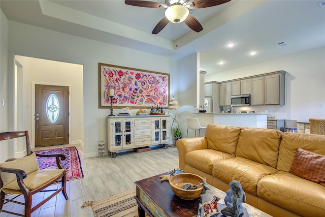 living room featuring ceiling fan, a raised ceiling, and light hardwood / wood-style flooring