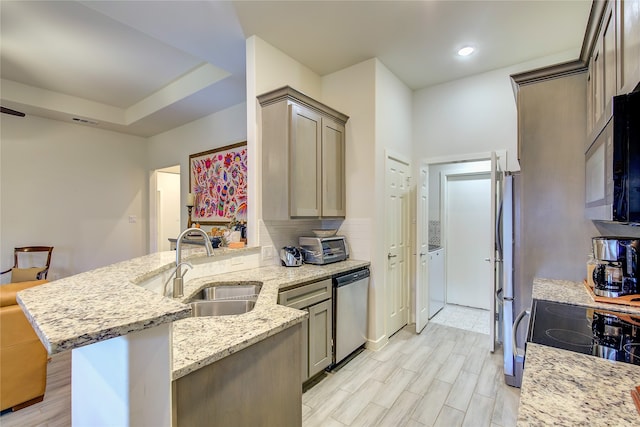 kitchen with light stone counters, sink, kitchen peninsula, appliances with stainless steel finishes, and a kitchen breakfast bar