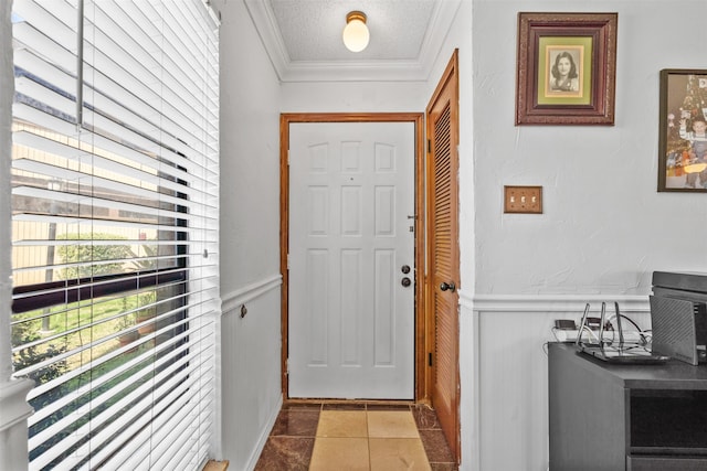 tiled entrance foyer with ornamental molding and a textured ceiling