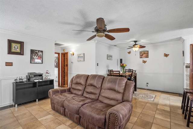 living room featuring ceiling fan, ornamental molding, and a textured ceiling