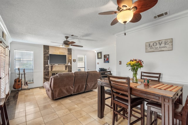 tiled dining room featuring ceiling fan, ornamental molding, and a textured ceiling