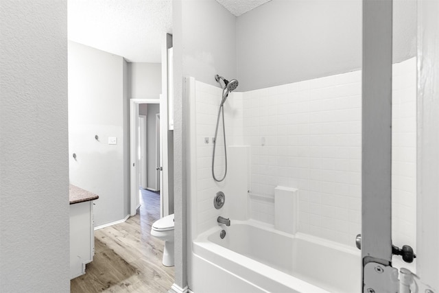 full bathroom featuring shower / bathtub combination, hardwood / wood-style flooring, vanity, toilet, and a textured ceiling