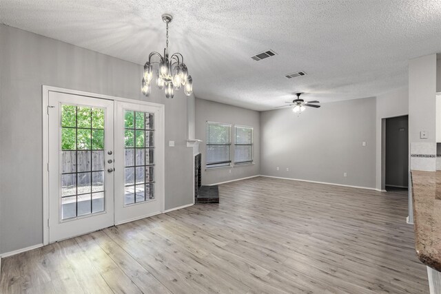 spare room with ceiling fan, brick wall, light wood-type flooring, and a textured ceiling