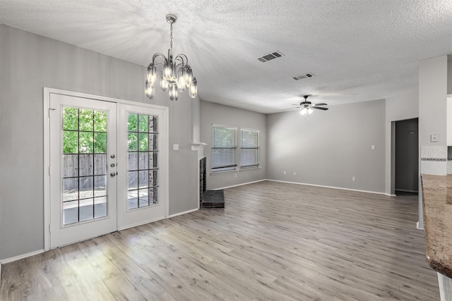 unfurnished living room with hardwood / wood-style floors, ceiling fan with notable chandelier, french doors, and a textured ceiling