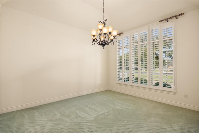 carpeted spare room featuring baseboards and an inviting chandelier