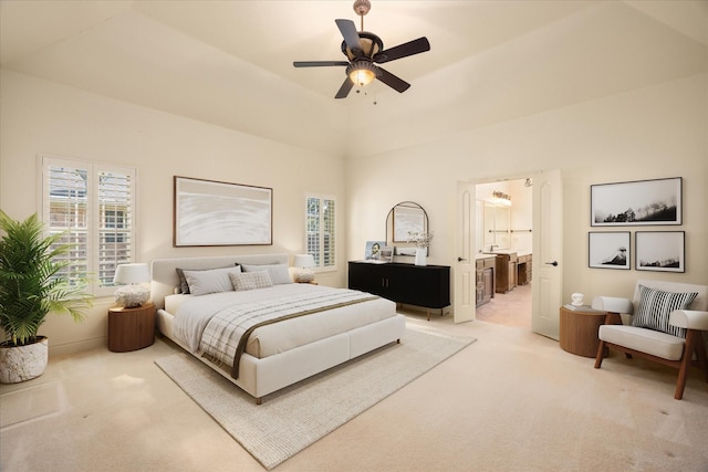 bedroom featuring a ceiling fan, light colored carpet, and ensuite bath